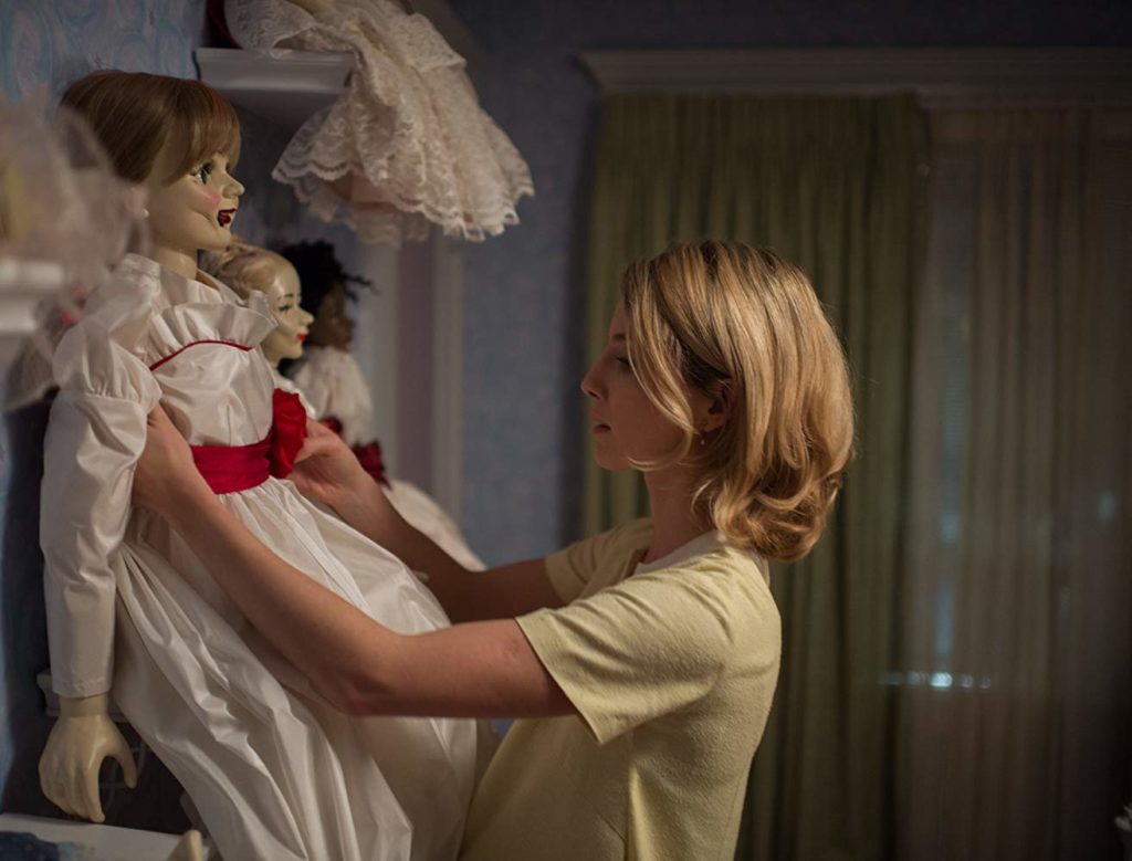 Moça loira posiciona a boneca Annabelle dentre suas outras bonecas. Maratona de Sofá.