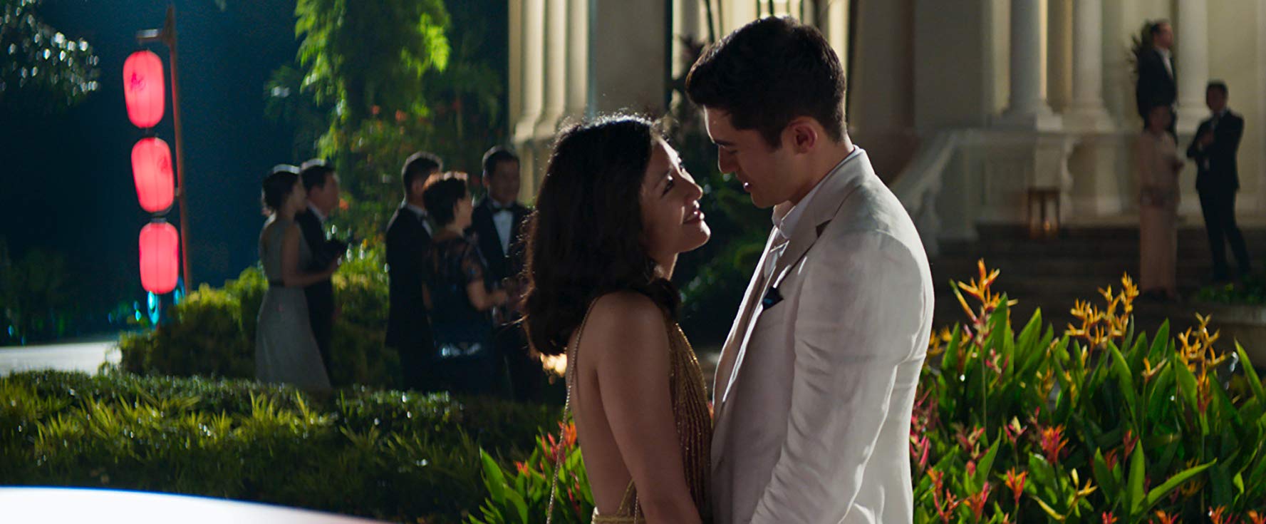 Rachel (Constance Wu) e Nick (Henry Golding) se olhando de forma apaixonado no jardim da mansão dos Young