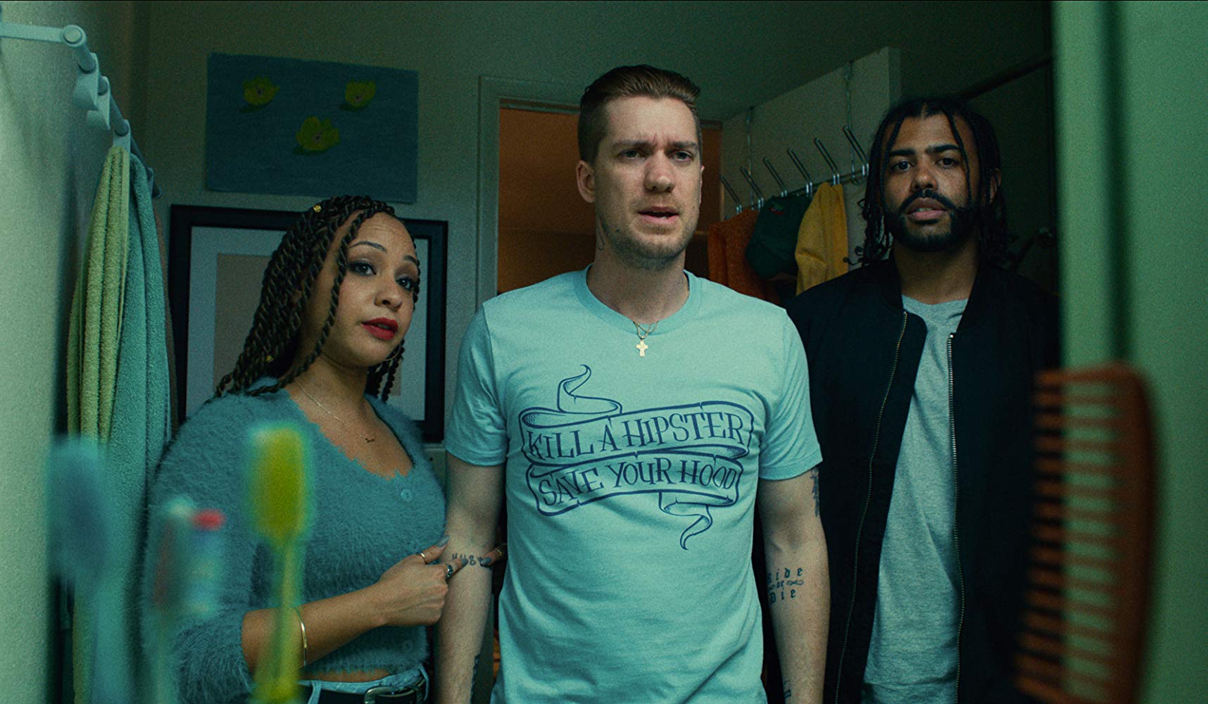 Se olhando no espelho, Miles olha a camiseta que recebeu de presente da esposa Ashley (Jasmine Cephas Jones), que está ao seu lado. Colin está do outro lado, olhando.