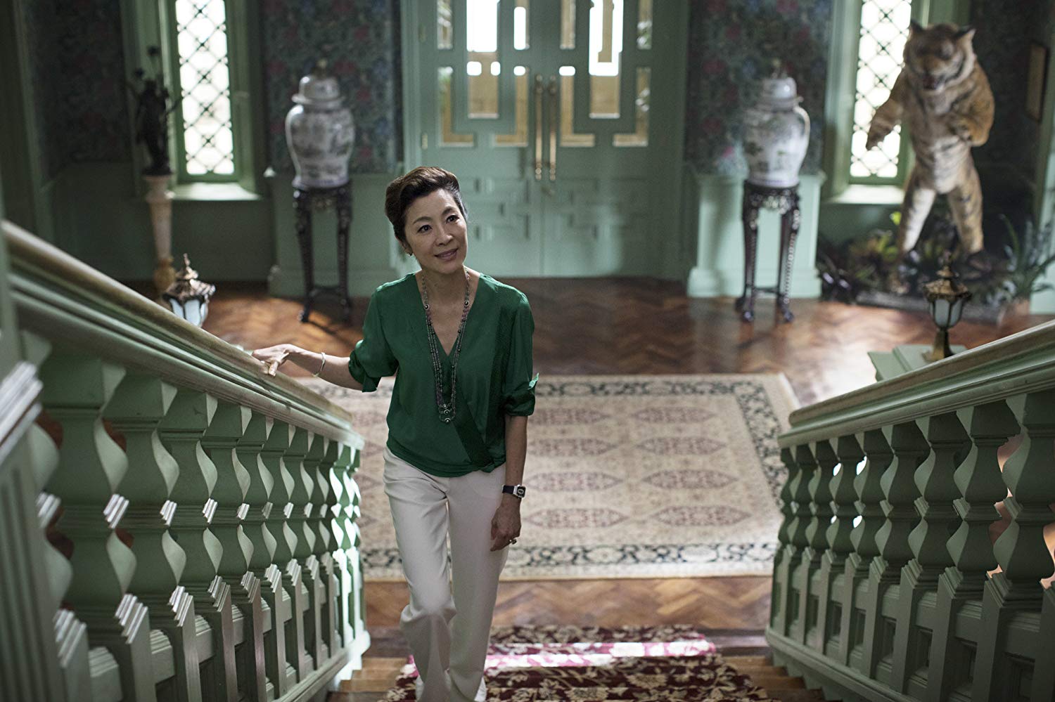 Eleanor (Michelle Yeoh) subindo as escadas da sua mansão. a câmera a olha de cima das escadas.