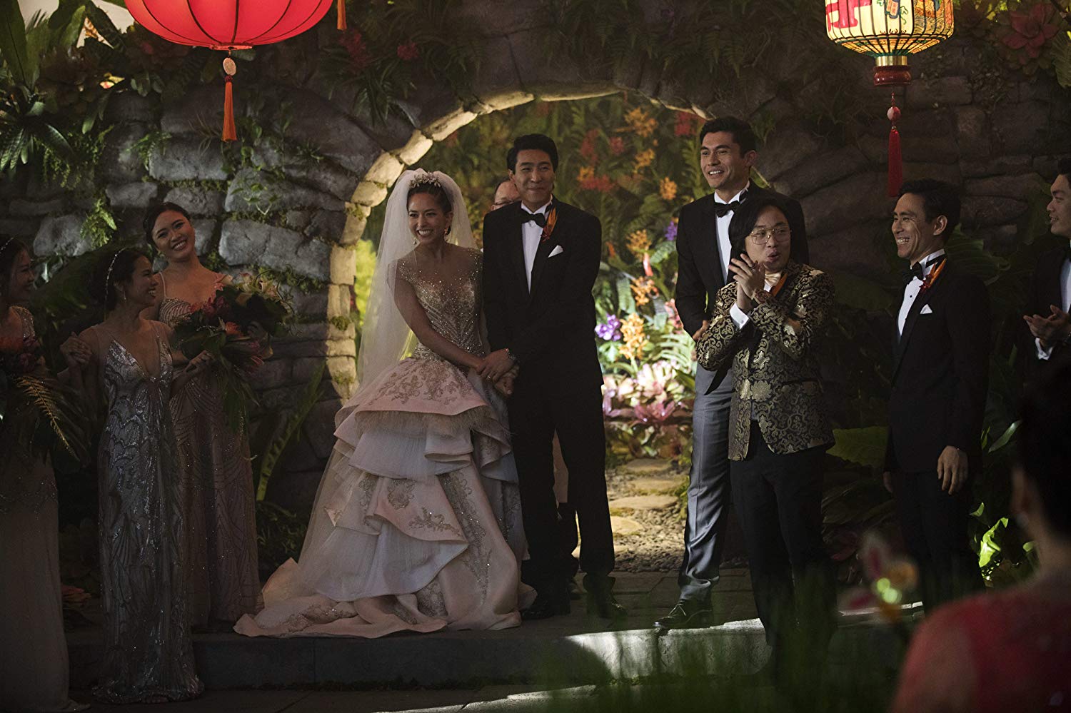 No centro do altar, os noivos Colin (Chris Pang) e Araminta (Sonoya Mizuno). Do lado direito, os padrinhos Bernard (Jimmy O. Yang), Shuhei Kinoshita, e Nick (Henry Golding). As madrinhas à esquerda não estão creditadas.