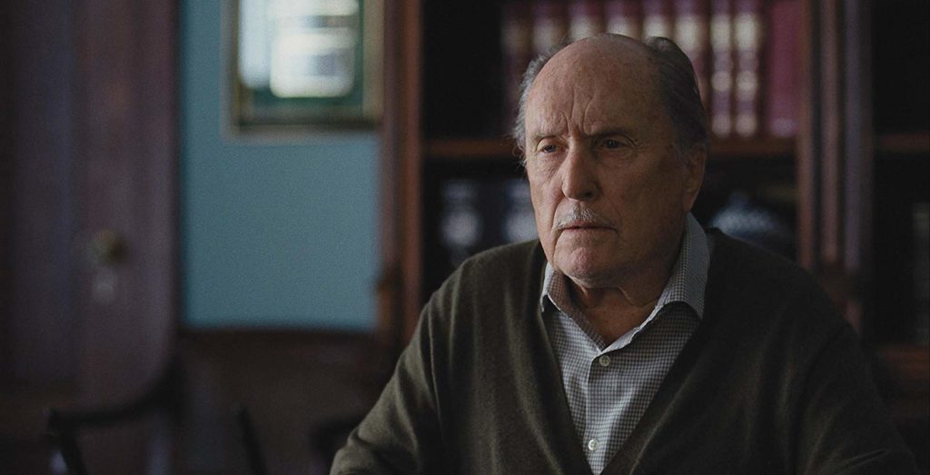 Robert Duvall, em close, olhando para além da mesa. Está num escritório