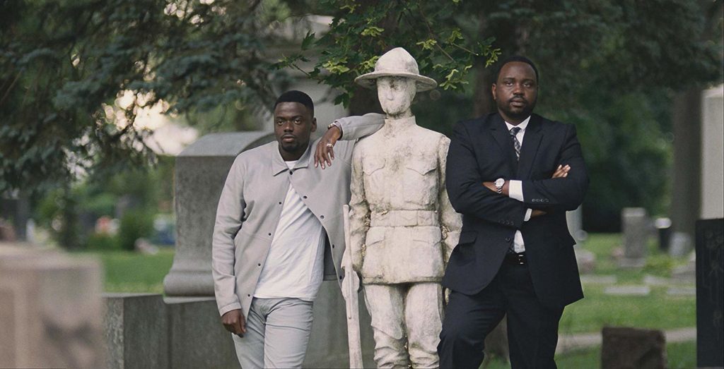 Jetemme (Daniel Kaluuya) e Jamal (Brian Tyree Henry) em um cemitério, apoiados numa estátua de soldado