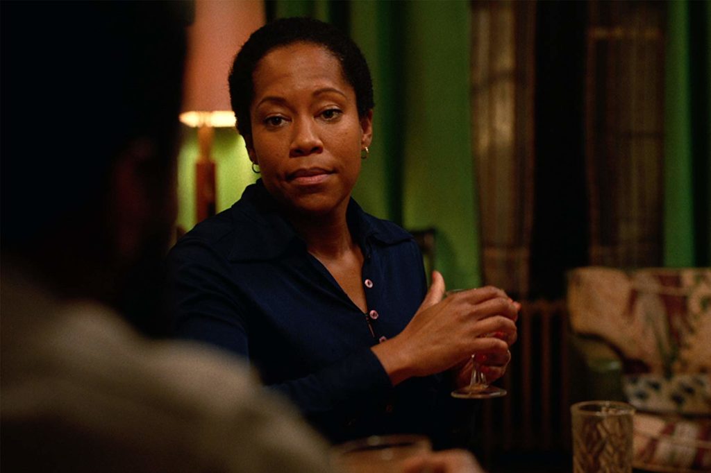 Sharon (Regina King) sentada no sofá, copo em mãos, olhando pacientemente para Tish (Fora de quadro)