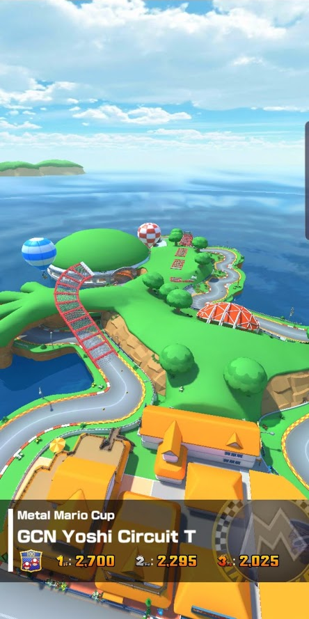Vista aérea da pista de uma corrida. Numa legenda se lê "Metal Mario Cup" numa primeira linha "GCN Yohsi Circuit T" numa segunda linha e a dificuldade e pontuações para as primeiras 3 colocações.