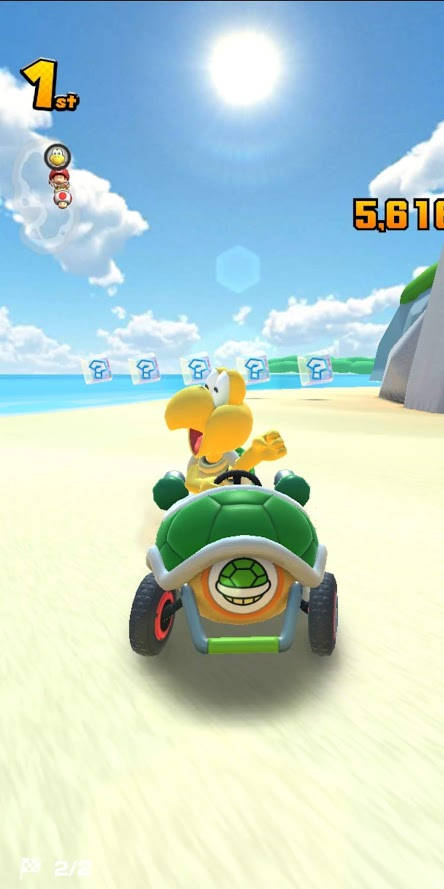 Koopa Troopa, personagem antagônico ao Mario, vence a corrida e está comemorando em primeiro plano no seu Kart.