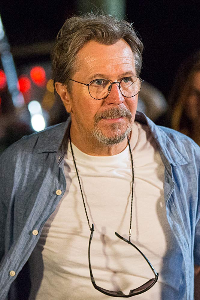 Em close, David (Gary Oldman) parece pensativo e agitado ao observar algo