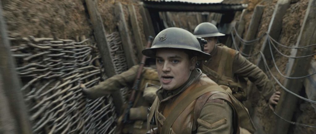 Em 1917, numa das trincheiras, Blake (a frente) anda em direção à câmera. Schofield o segue logo de perto