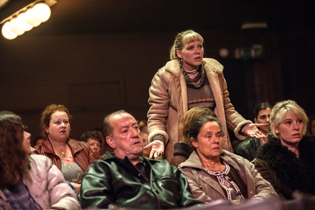 Dentre várias pessoas sentadas num auditório, assistindo alguém, Tanya (Léa Seydoux) está de pé, parecendo indignada, interpelando quem está ministrando a fala (fora do quadro)