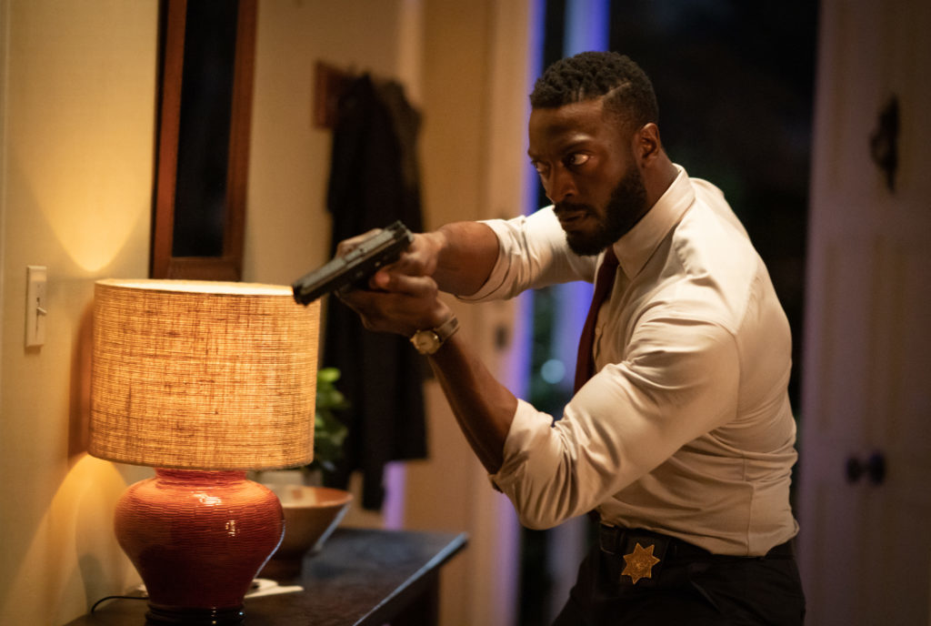 James (Aldis Hodge) está dentro de casa, trajando roupa social (pois veio do trabalho (qual a relevância disso? não sei)), com arma em riste, e claramente tenso, como procurando por alguém