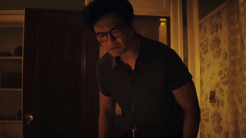 Peter Spencer (John Cho) esté levemente envergado, entrando num banheiro com baixa iluminação, olhando preocupado para algo