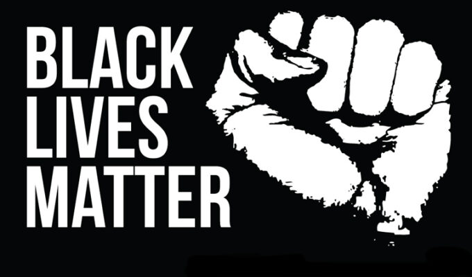 imagem em preto e branco. Na esquerda, se lê "BLACK LIVES MATTER". Na direita, um punho fechado, erguido. in Posicionamento em Junho/2020