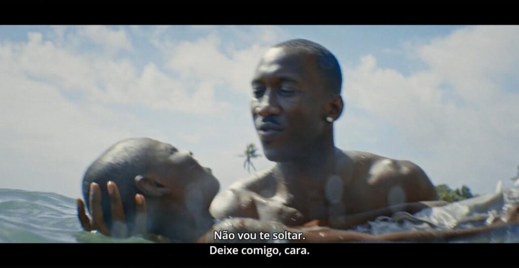 ena do filme Moonlight: Juan e Chiron estão dentro do mar. Juan está segurando Chiron, tentando fazê-lo boiar.  Ele diz (lemos na legenda) "Não vou te soltar. Deixe comigo, cara."