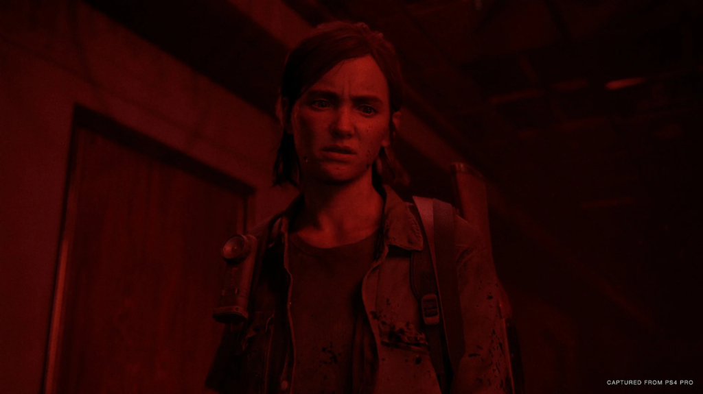 Ellie num corredor, banhada de uma luz vermelha