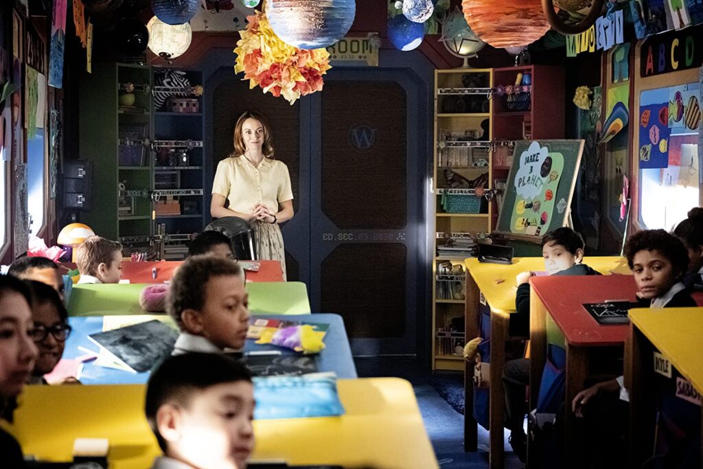 No vagão escolar do Snowpiercer, várias crianças (incluindo Miles) estão olhando para trás, como se ouvindo alguém. Na frente da sala, a Sr. Gillies (Fiona Vroom) observa com orgulho