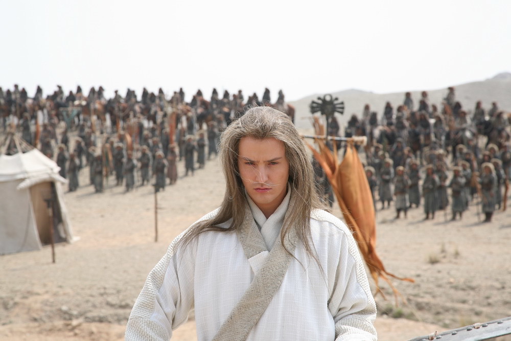 O cantor VITAS, usando as roupas que caracterizam seu personagem, Wude. Ele está em pé num campo militar no deserto. Ao fundo, à média distância, vemos vários soldados em pé. No meio do caminho vemos parcialmente uma barraca montada como panos e madeira
