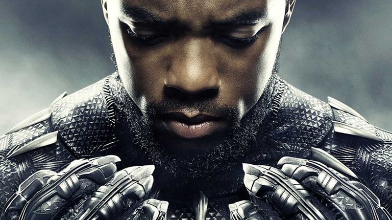 Foto em close de Chadwick, vestido de Pantera (mas sem a máscara), com o rosto encarando as mãos