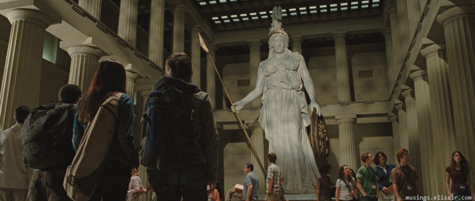 Percy, Grover e Annabeth de costas encarando uma estátua da deusa Atena dentro de uma galeria de museu