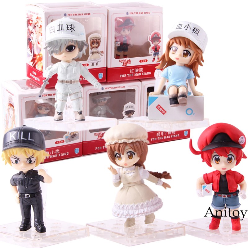 Fotografia com action figures dos personagens de Cells at Work! em formato Chibii: Ao fundo, vemos as caixas dos brinquedos, e em primeiro plano (da esquerda para a direita, de cima para baixo) O Neutrófilo, a Plaqueta, a T Citotóxica, a Macrófago e a Glóbulo Vermelho