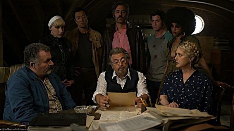 Os caçadores estão reunidos ao redor de uma mesa com Meyer Offerman (Al Pacino), analisando documentos com uma expressão preocupada.