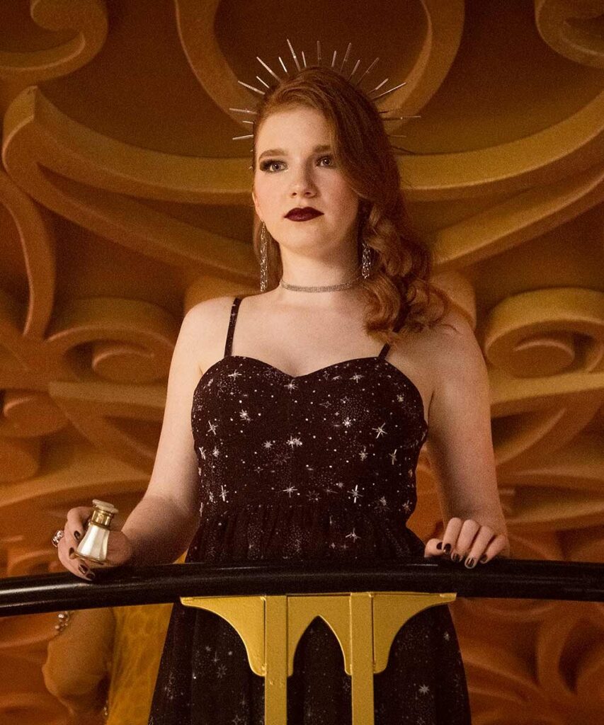 No mezanino, LJ está com vestido preto, com estampa de estrelas, com um binóculo na mão direita (ambas mãos apoiadas na balaustrada). Ela tem uma tiara de espinhos, que emulam uma aura. Lembra pinturas religiosas