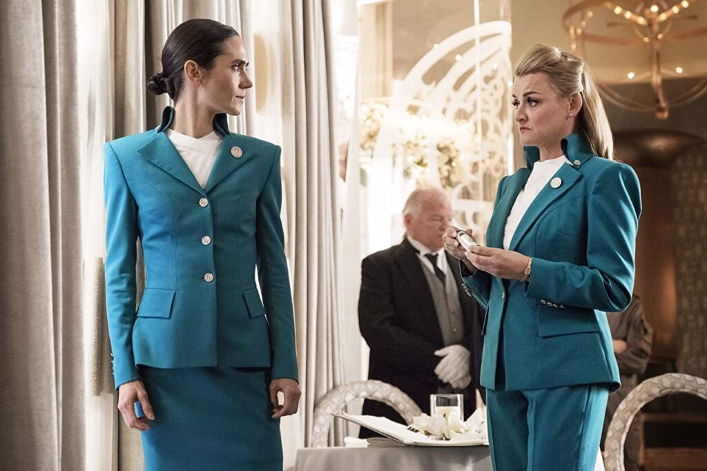 Na primeira classe do Snowpiercer, Melanie e Ruth conversam secretamente. Ao fundo, um mordomo