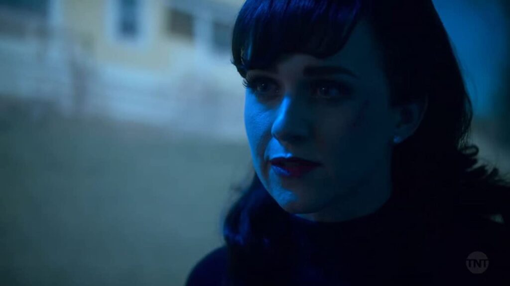 Em close, Audrey toda de preto, com cabelo encaracolado e franjas. Em Snowpiercer