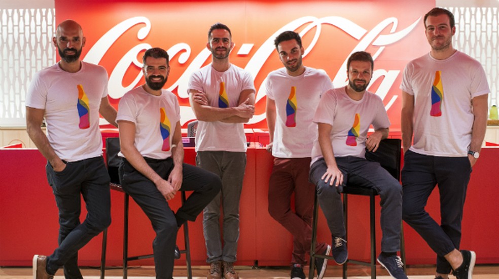 fotografia do grupo de diversidade da Coca-Cola. São 6 homens brancos, bastante parecidos, alternados entre sentar numa banqueta, ou em pé. Estão sorrindo.