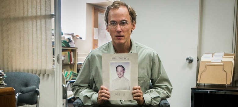 Phil Saviano contando sobre seu caso de abuso por mão de um padre, demonstrando sua foto mais jovem