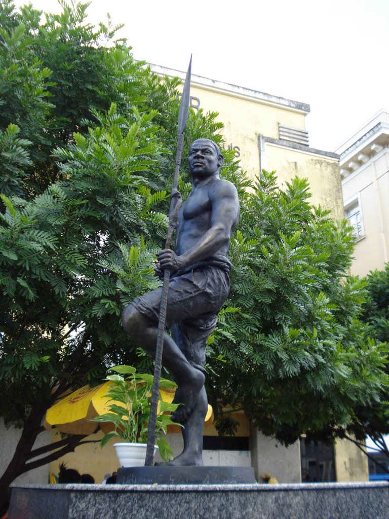 Estátua de Zumbi dos palmares, no Pelourinho, em Salvador-Ba. É um homem negro (obvio) em pé, com o pé esquerdo se apoiando no joelho direito. Ele usa uma bermuda (que aparenta ser de algodão grosso), e segura uma lança na mão esquerda. Ele olha para a esquerda, como que olhasse para além da lança. A única vestimenta que ele usa é a bermuda. Tem um corpo musculoso e saudável. Atrás da estátua, vemos um prédio (antigo cinema), as folhagens de uma árvore, e um guarda-sol, certamente usado por algum vendedor ambulante, com marca de cerveja estampada.
No editorial Mês Negro no Maratona