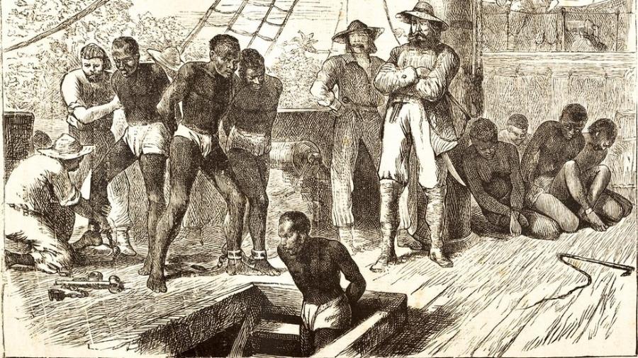 Gravura de pessoas negras sendo escravizadas sendo conduzidas em navios negreiros. alguns estão sendo arrastados por homens brancos, outros estão sentado e amarrados. Alguns estão descendo as escadarias para a parte inferior do navio. Dois homens brancos olham para os negros com superioridade. Zumbi.