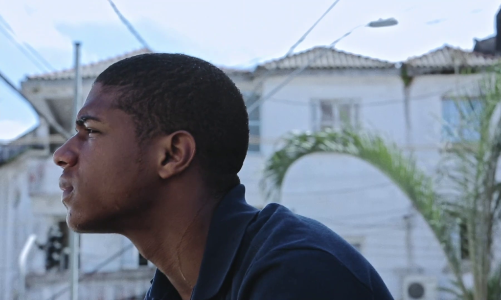 Sòcrates olha para o horizonte, suado. Há casas em desfoque ao fundo. "Sócrates é um desabafo gay e preto"