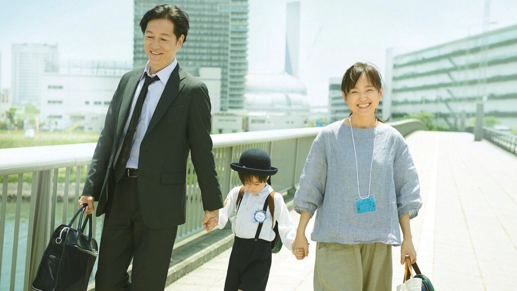 Imagem de Mães de Verdade. O casal Satoko e Kiyokazu estão andando, segurando (cada um) os bracinhos de Asato.