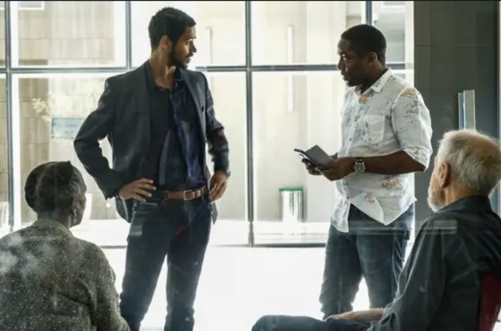 Lázaro conversa com Alfred Enoch. Os pais de Alfred estão próximos, atentos à conversa.