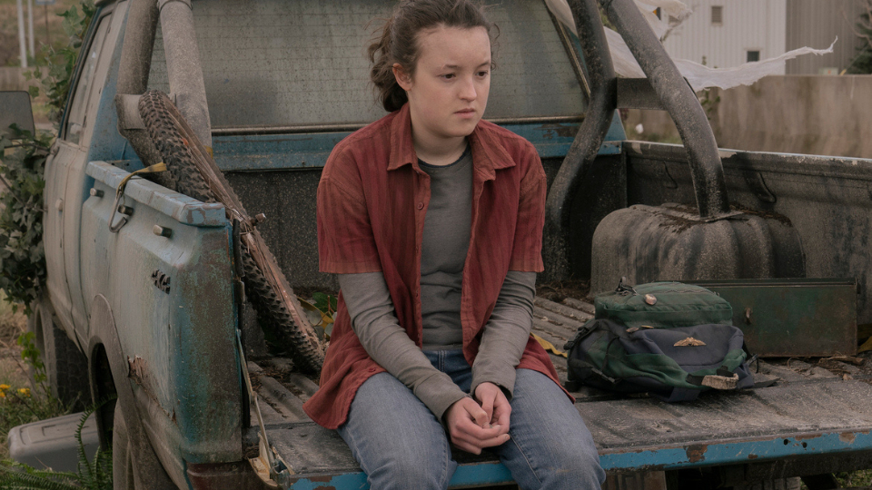 Cena de The Last of US, onde Ellie (Bella Ramsay) sentada numa picape, com olhar perdido.